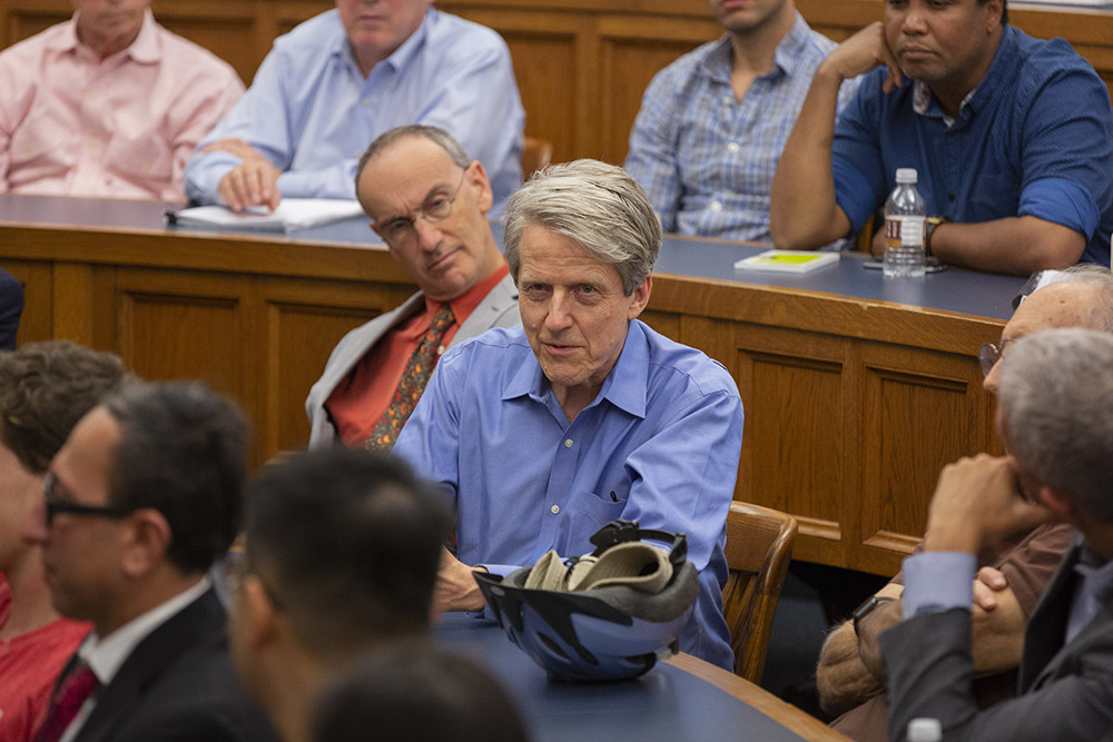 Yale Econ. and SOM Prof. Robert Shiller asking NYU Stern Econ. Prof. Lord Mervyn King a question, while Yale University Provost and Yale Econ. and SOM Prof. Benjamin Polak (left) and others listen