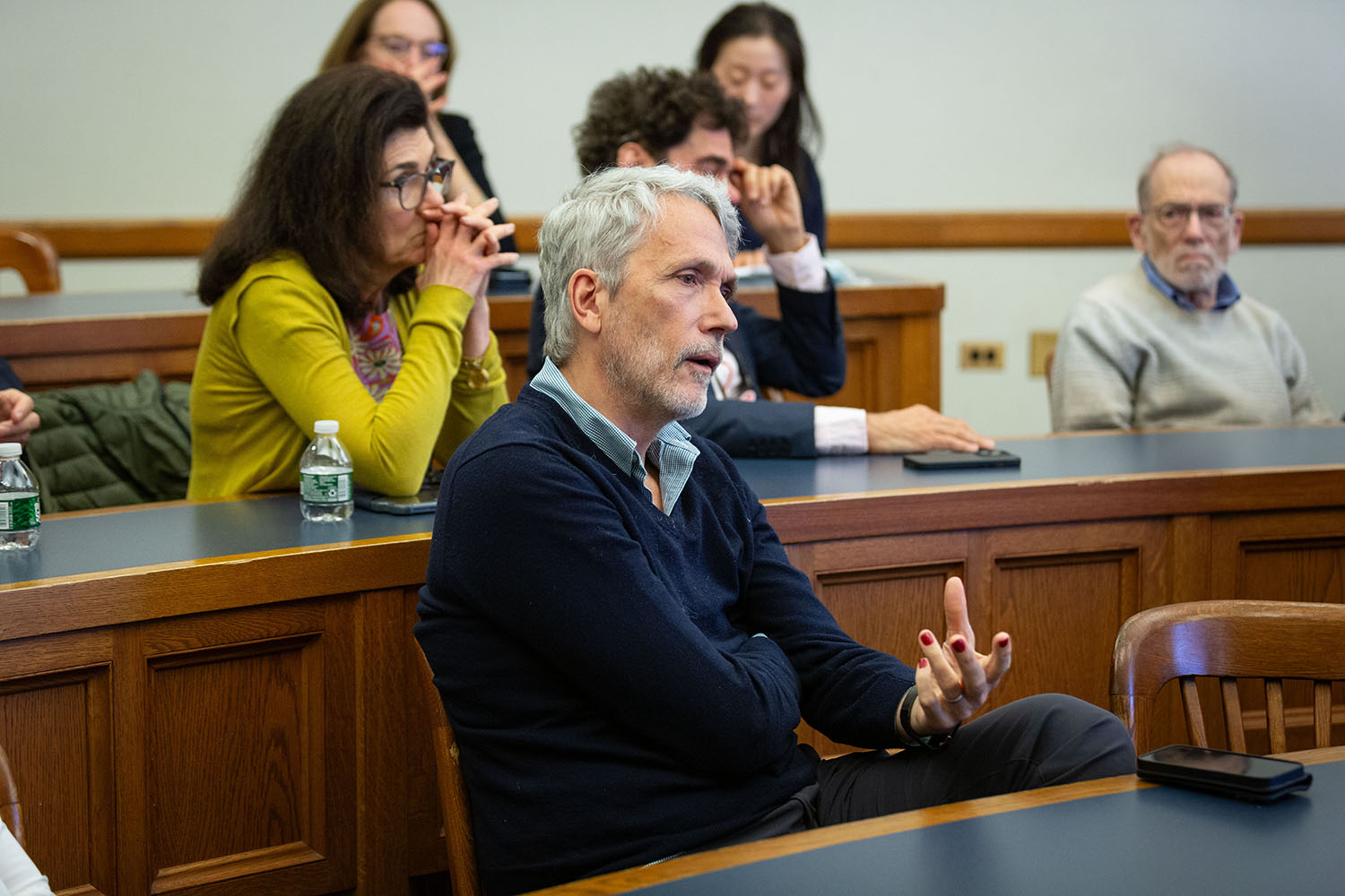 YLS Prof. Ian Ayres &#039;86 (foreground) asking a question, while Marianna Ayres, Yale Econ. Prof. John Geanakoplos, and YLS Prof. Al Klevorick (background) listen